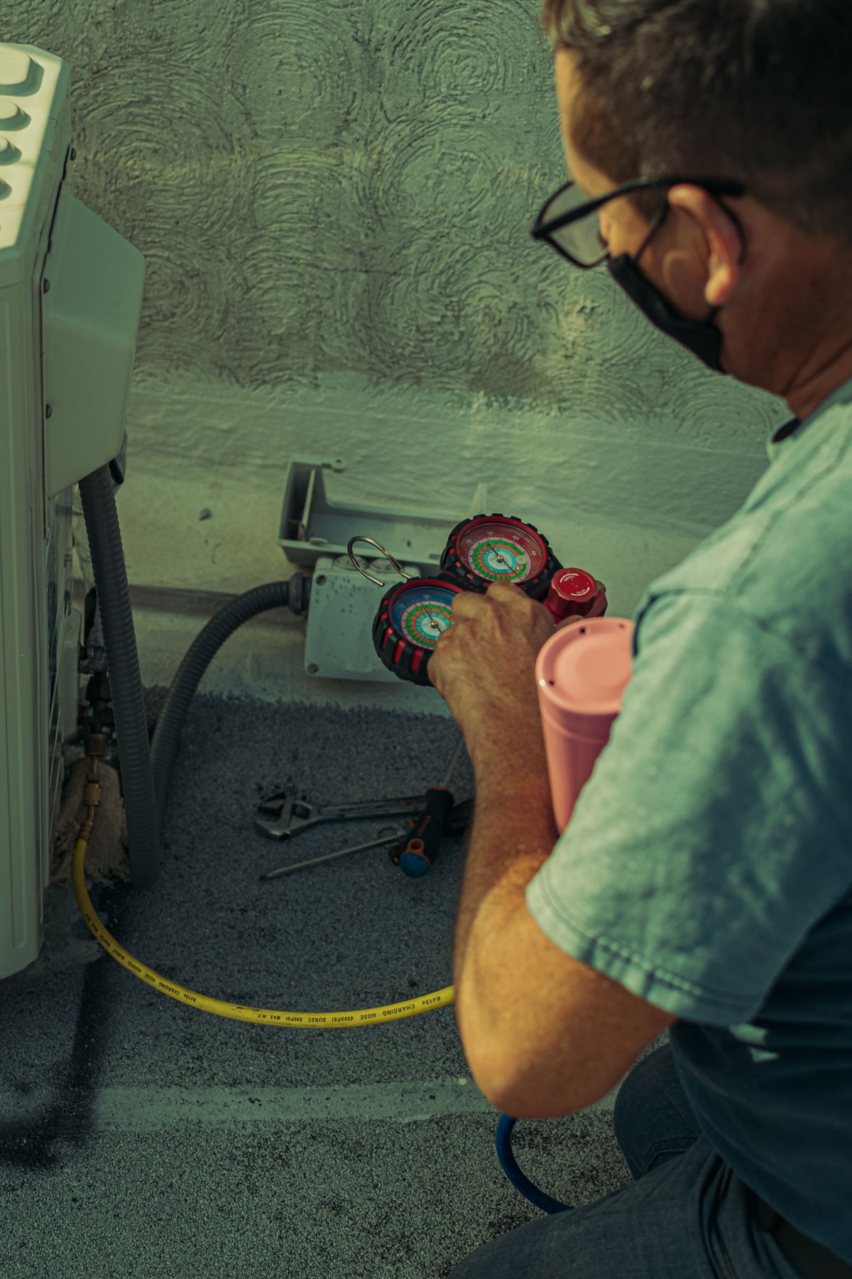 A technician checking refrigerant pressure gauges during an air conditioning service